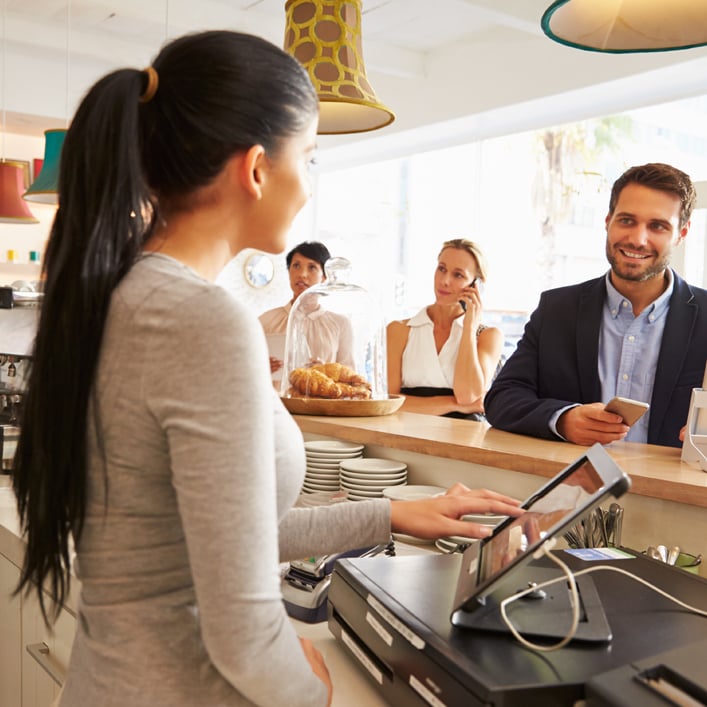 a girl standing on a billing counter and in front numerous people standing for their orders