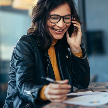 a women laughing holding a phone and a pen