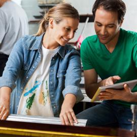 A man and women talking about something and the man is holding a tab